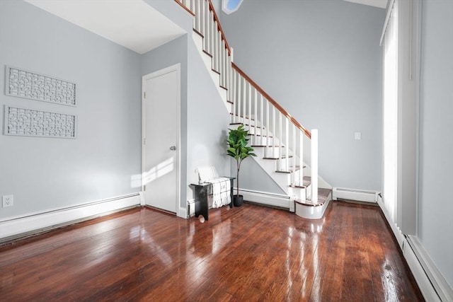 entrance foyer with a baseboard heating unit and dark hardwood / wood-style flooring