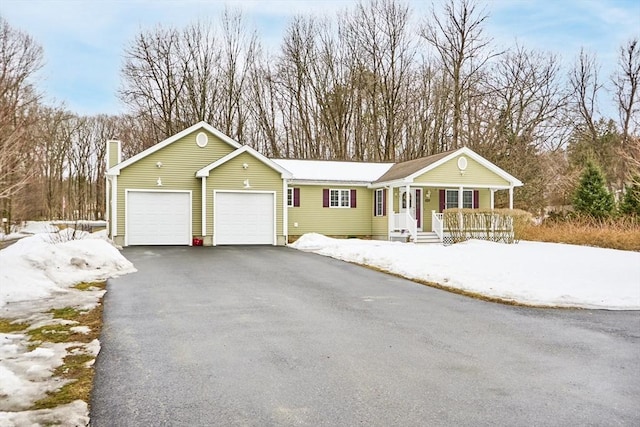 single story home with an attached garage, covered porch, driveway, and a chimney