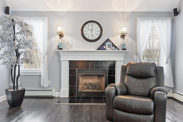 sitting room with wood finished floors, baseboards, baseboard heating, and a tile fireplace