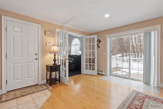 entryway with french doors, wood finished floors, baseboards, and a baseboard heating unit