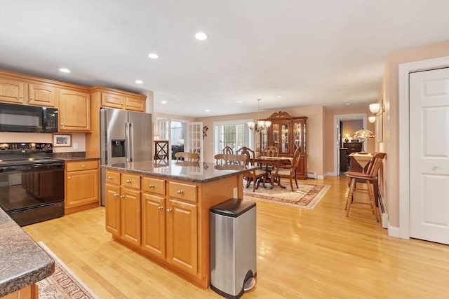 kitchen featuring light wood finished floors, recessed lighting, a center island, and black appliances