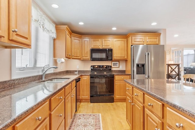 kitchen with a sink, dark stone counters, plenty of natural light, and black appliances