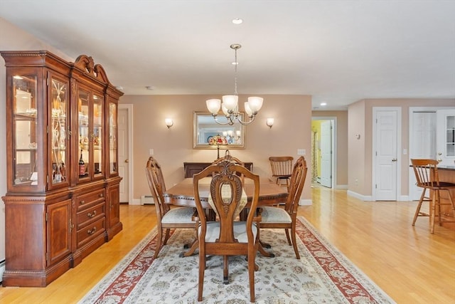 dining area with recessed lighting, baseboards, an inviting chandelier, and light wood finished floors