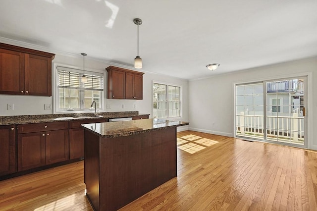 8 School St Unit 1, Waltham, MA 02452 - kitchen with light wood-type flooring, dark stone counters, pendant lighting, a kitchen island, and a sink