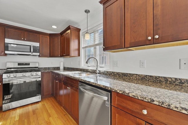 8 School St Unit 1, Waltham, MA 02452 - kitchen with stainless steel appliances, a sink, dark stone counters, light wood-style floors, and hanging light fixtures