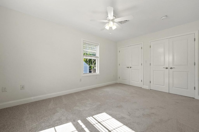 8 School St Unit 1, Waltham, MA 02452 - unfurnished bedroom with two closets, light carpet, baseboards, and a ceiling fan