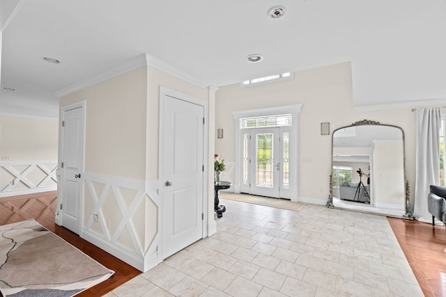 foyer with crown molding, french doors, and light wood-type flooring