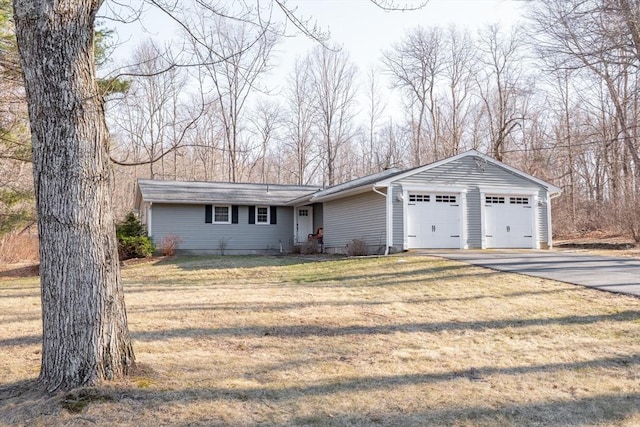 ranch-style house with a front lawn, an attached garage, and driveway