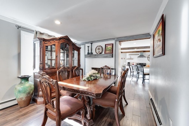 dining area featuring a baseboard radiator, wood finished floors, and crown molding