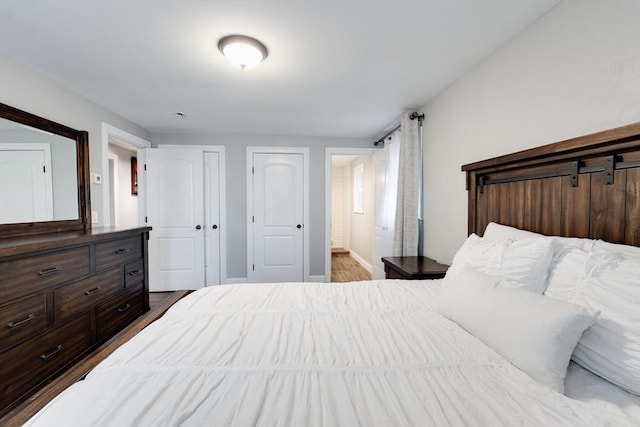 bedroom with ensuite bath, baseboards, and wood finished floors