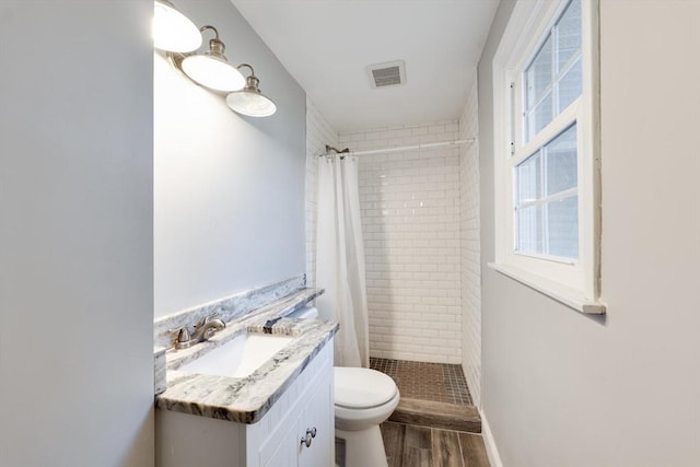 full bath featuring vanity, toilet, wood finished floors, and a stall shower