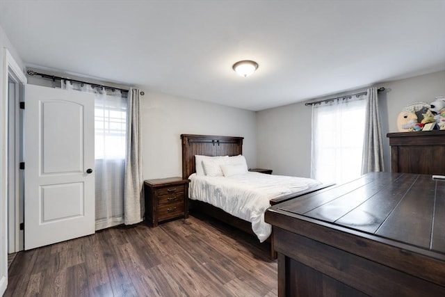 bedroom with multiple windows and dark wood-style flooring