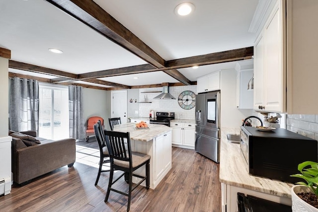 kitchen with a sink, stainless steel appliances, dark wood-type flooring, and wall chimney range hood