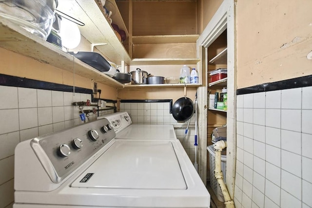 laundry area with tile walls and washer and dryer