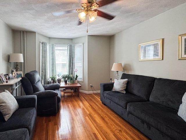 living area with a ceiling fan, light wood-style floors, a textured ceiling, and baseboards