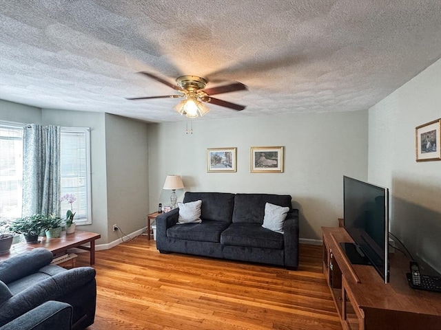 living room with light wood-type flooring, a textured ceiling, a ceiling fan, and baseboards