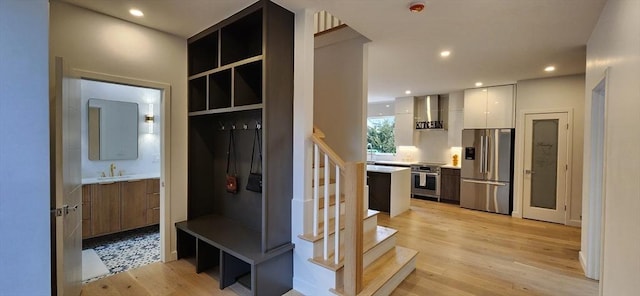 mudroom with light wood-type flooring, a sink, and recessed lighting