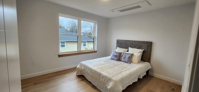 bedroom with wood finished floors, visible vents, and baseboards