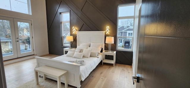 bedroom featuring access to exterior, refrigerator, multiple windows, and light wood-style flooring