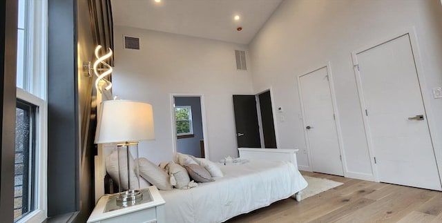 bedroom with light wood finished floors, visible vents, high vaulted ceiling, and recessed lighting