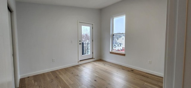 spare room with light wood-style flooring, a wealth of natural light, and baseboards