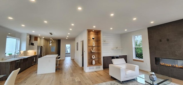 living area featuring light wood-type flooring, a wealth of natural light, a fireplace, and recessed lighting