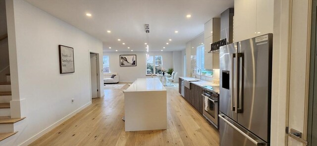 kitchen featuring wall oven, a sink, light countertops, freestanding refrigerator, and modern cabinets