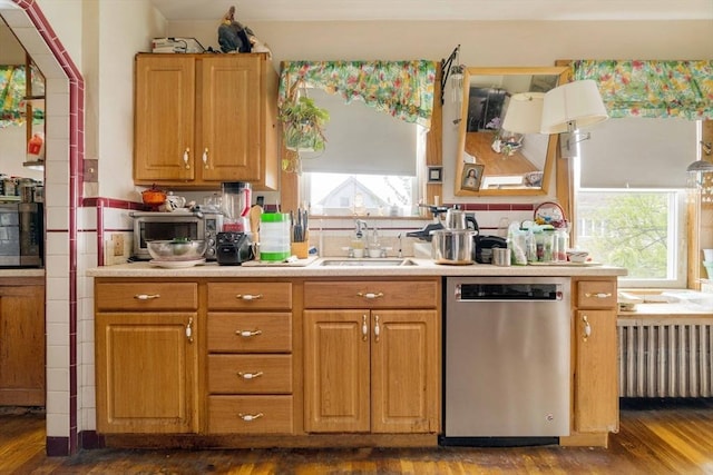kitchen with stainless steel dishwasher, a sink, dark wood finished floors, light countertops, and radiator heating unit