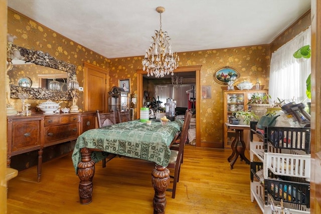 dining room featuring wallpapered walls, a chandelier, and wood finished floors