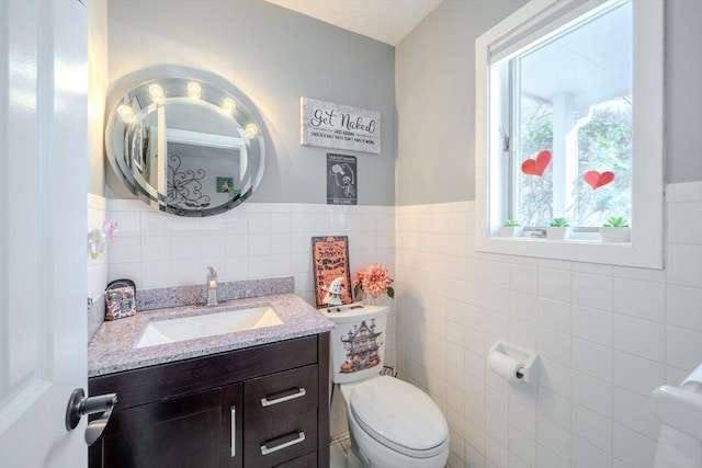 bathroom with tile walls, toilet, and vanity