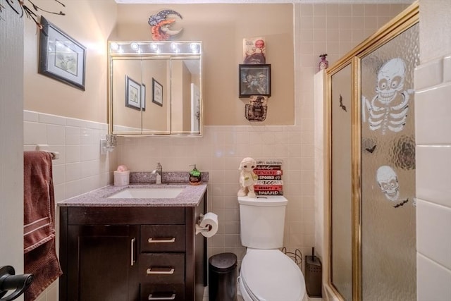 bathroom featuring tile walls, toilet, a shower stall, and vanity