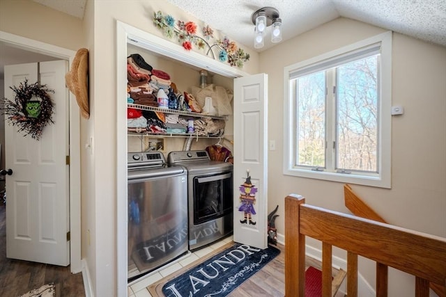 laundry area featuring a textured ceiling, laundry area, wood finished floors, baseboards, and washing machine and clothes dryer