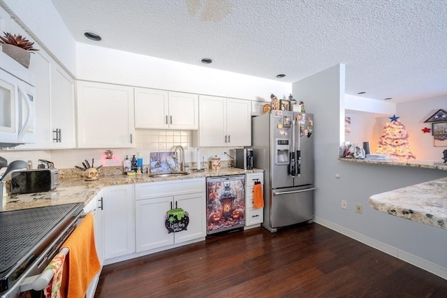 kitchen with white microwave, dark wood-style flooring, a sink, light stone countertops, and stainless steel fridge