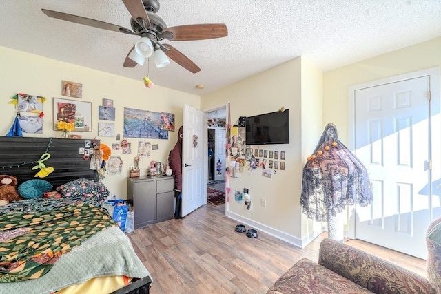 bedroom featuring baseboards, a textured ceiling, a ceiling fan, and wood finished floors