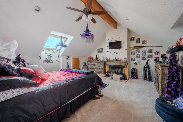 bedroom featuring a fireplace with raised hearth, a ceiling fan, vaulted ceiling with beams, a textured ceiling, and carpet flooring