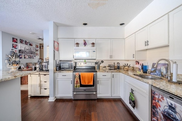 kitchen with appliances with stainless steel finishes, dark wood finished floors, white cabinetry, and a sink