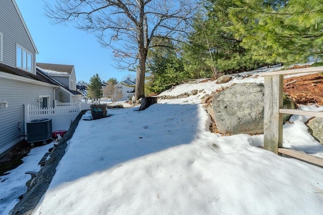 snowy yard with fence and central AC