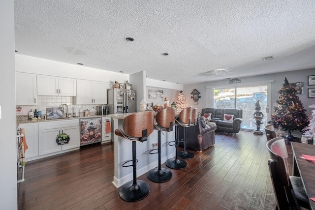 kitchen with white cabinets, dark wood-type flooring, a center island, a kitchen bar, and stainless steel refrigerator with ice dispenser