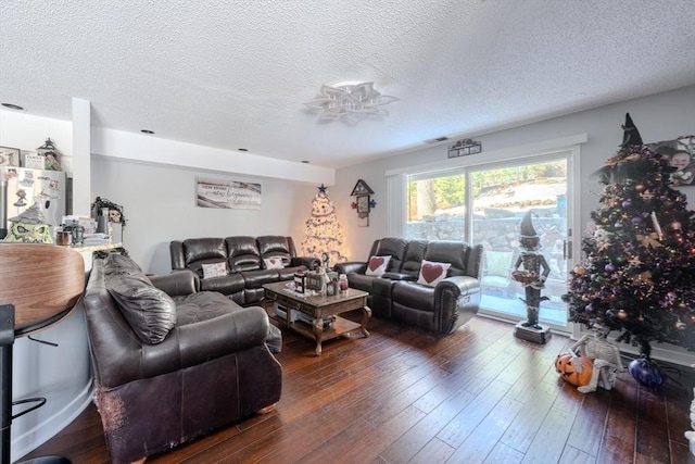 living room with visible vents, dark wood finished floors, and a textured ceiling