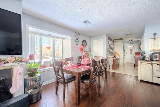 dining room featuring baseboards, a textured ceiling, visible vents, and dark wood-style flooring