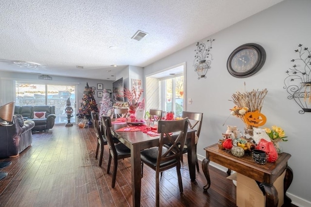 dining room featuring a textured ceiling, dark wood-style flooring, visible vents, and baseboards