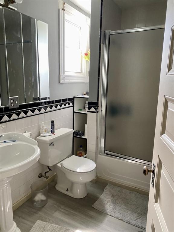 257 French St, Fall River, MA 02720 - bathroom with toilet, wood finished floors, tile walls, combined bath / shower with glass door, and a wainscoted wall