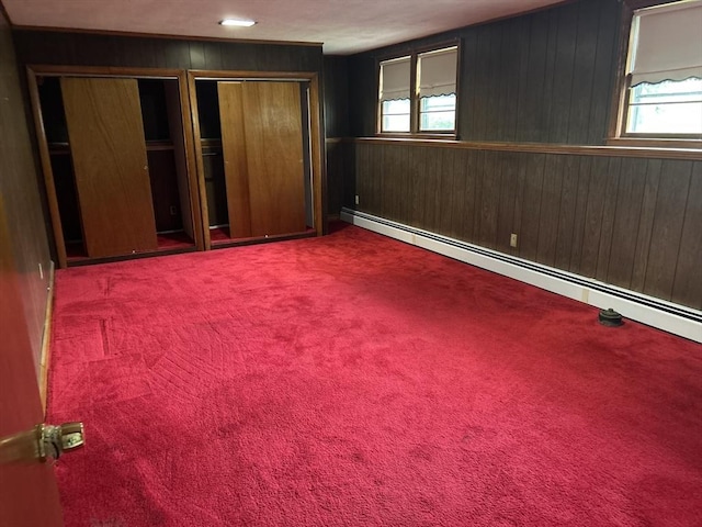 14 Rogers Cir, Braintree, MA 02184 - unfurnished bedroom with a baseboard radiator, multiple closets, multiple windows, wood walls, and carpet flooring