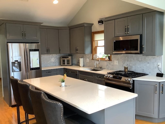 11 Dyer, Everett, MA 02149 - kitchen featuring appliances with stainless steel finishes, a sink, gray cabinetry, vaulted ceiling, and a kitchen breakfast bar