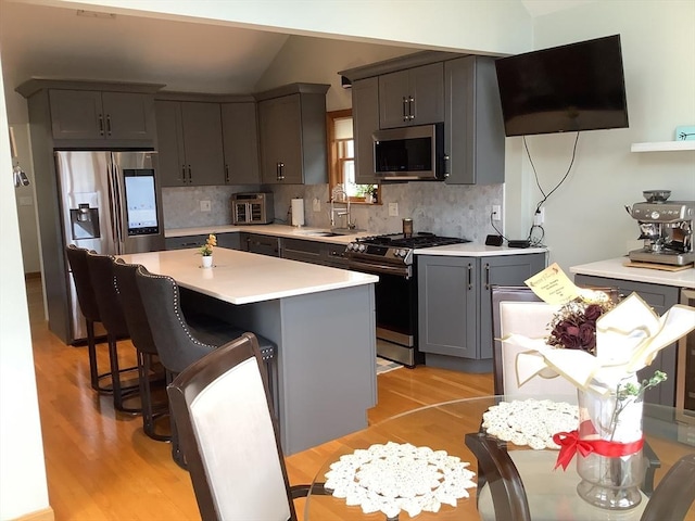 11 Dyer, Everett, MA 02149 - kitchen with stainless steel appliances, a sink, light wood-type flooring, light countertops, and decorative backsplash