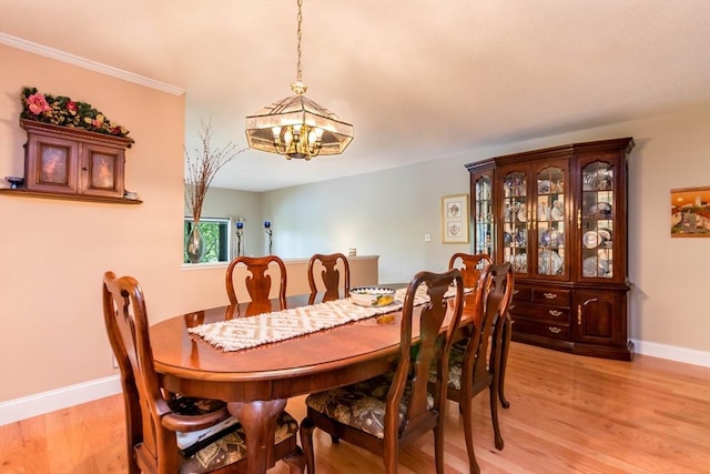dining area featuring a chandelier, light wood-style flooring, and baseboards