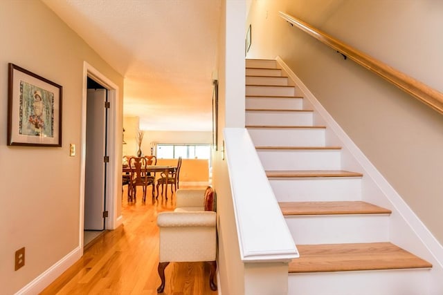 stairs featuring wood finished floors and baseboards