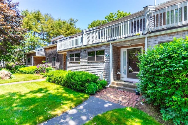 property entrance with a balcony and a lawn