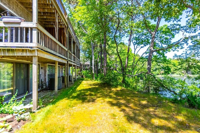 view of grassy yard with central AC unit and a wooden deck