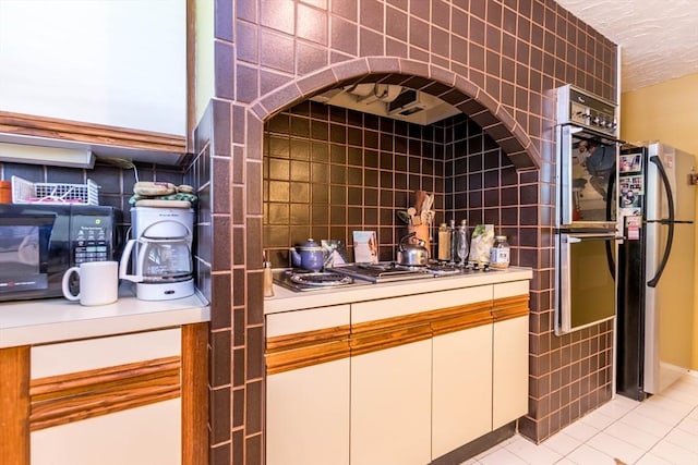detailed view of stainless steel appliances, tile walls, tasteful backsplash, and a textured ceiling